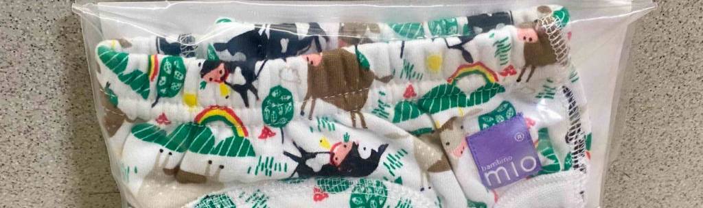 Töpfchen-Trainingshose im Test: das Baby-Höschen im bunten Tier-Design steckt in einer transparenten Kunststofftüte, die an einer Marmorwand lehnt.