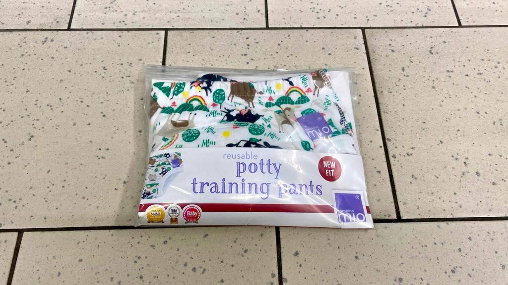 Töpfchen-Trainingshosen-Test: ein Modell im bunten Tier-Design befindet sich in einer transparenten Kunststofftüte auf einem beigefarbenen Fliesenboden.