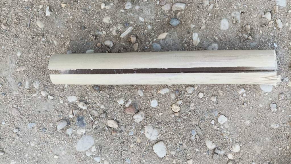 Ein getestetes Bambusröhrchen liegt auf einem Sandboden.