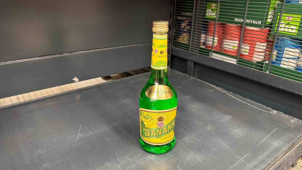 In einem grauen Regal steht eine Flasche des getesteten Bananenlikörs.