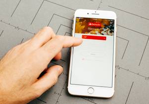 Banking-Software für den Mac im Vergleich: Ein iPhone mit geöffneter Banking-App liegt auf einem Tisch.