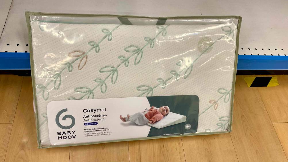 Keilkissen getestet: Ein verpacktes Produkt lehnt an einem Regalboden auf einer Holzfläche.