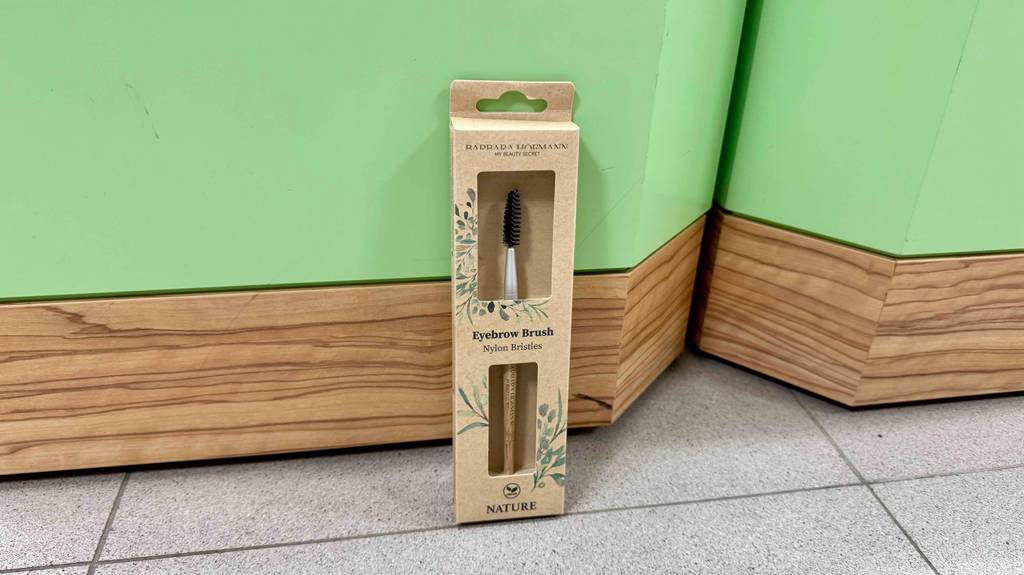 Ein getesteter, verpackter Augenbrauenpinsel steht auf einem Boden.