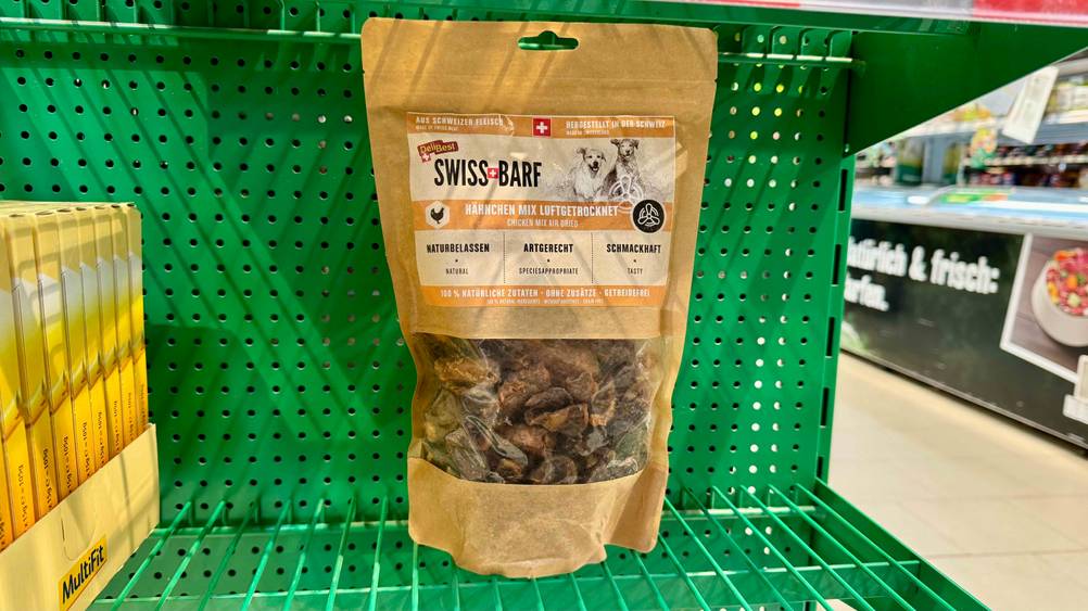 In einem grünen Regal steht eine Packung des BARF-Hundefutters im Test.