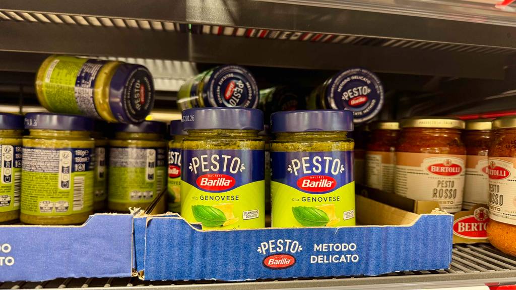 Pesto Genovese im Test: Mehrere Gläser stehen und liegen auf-, neben- und hintereinander in einem Regal.