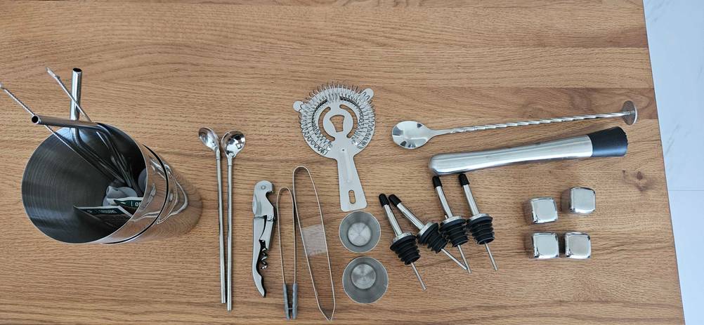 Alle Einzelteile eines getesteten Barkeeper-Set von oben angeordnet auf einer Holzfläche.