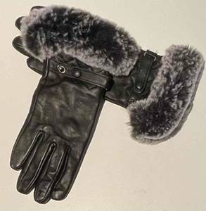 Schwarze Damen-Handschuhe aus Leder im Test mit dekorativem Kunstfellbesatz liegen auf einem hellen Untergrund.