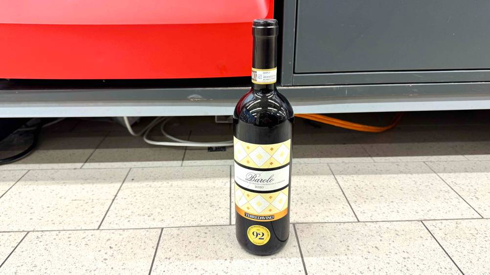 Vor einem Regal auf dem Boden steht ein getesteter Barolo-Wein.
