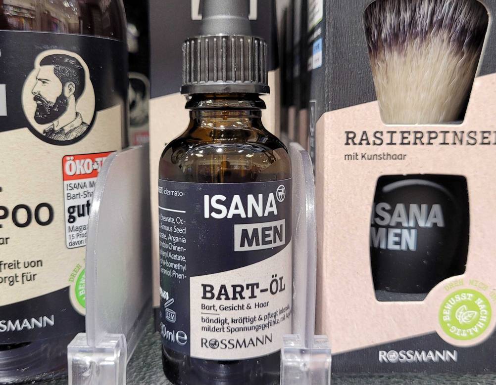 Eine Flasche Bartöl im Test steht zwischen anderen Produkten in einem Verkaufsregal.