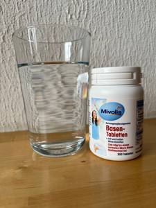 Mivolis-Tabletten mit einem Wasserglas.