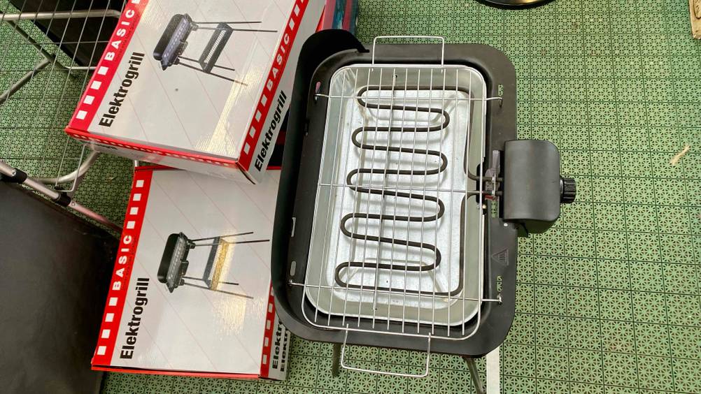 Ein getesteter Elektrogrill von oben auf einer grünen Fläche stehend.