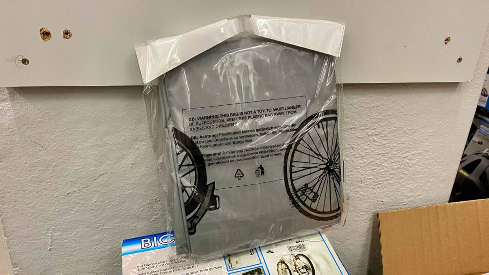 Fahrradschutzhülle getestet: Eine verpackte Hülle in grau vor einer hellen Wand auf einem Karton.