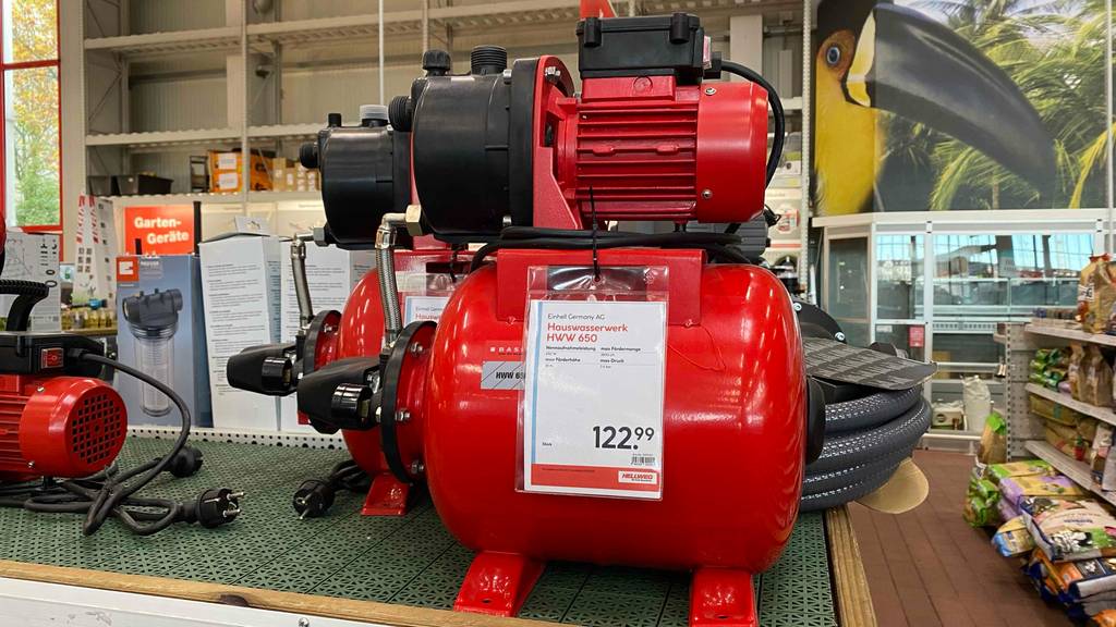 Ein rotes, getestetes Hauswasserwerk der Marke Einhell steht inklusive Preisschild in einem Verkaufsbereich.