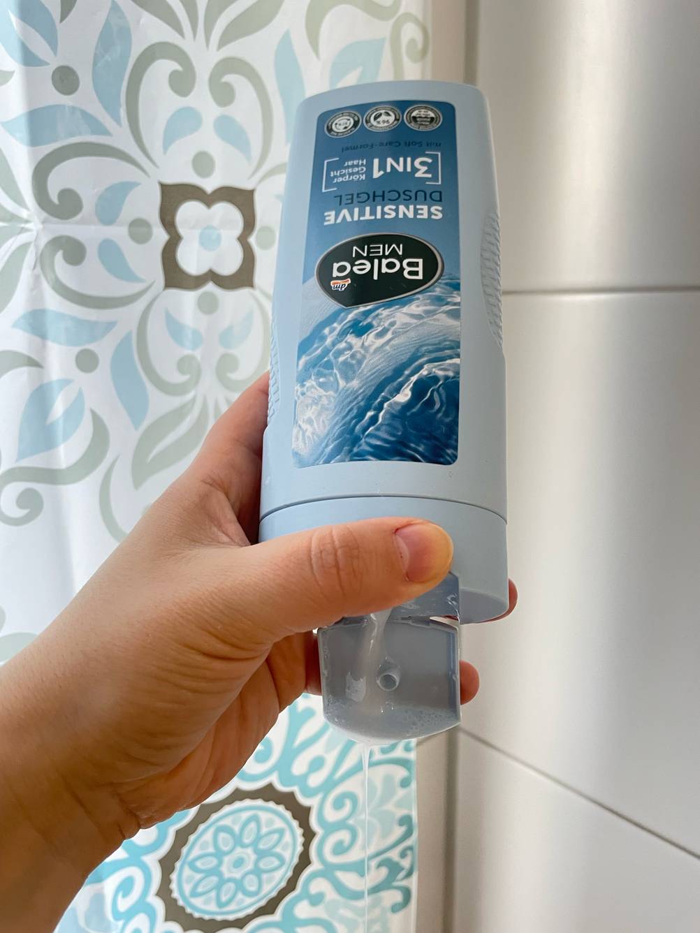 Eine Hand hält eine Flasche des getesteten basischen Duschgels hoch.