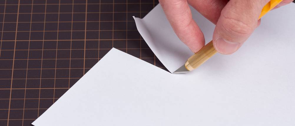Bastelmesser-Test: eine Person schneidet mit einem Bastelmesser Papier