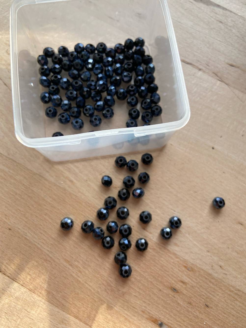 Neben der Dose liegen die getesteten Bastelperlen in schwarz.