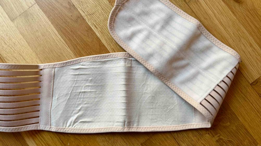 Auf einem Holzboden liegt der aufgefaltete Bauchgurt Schwangerschaft im Test.