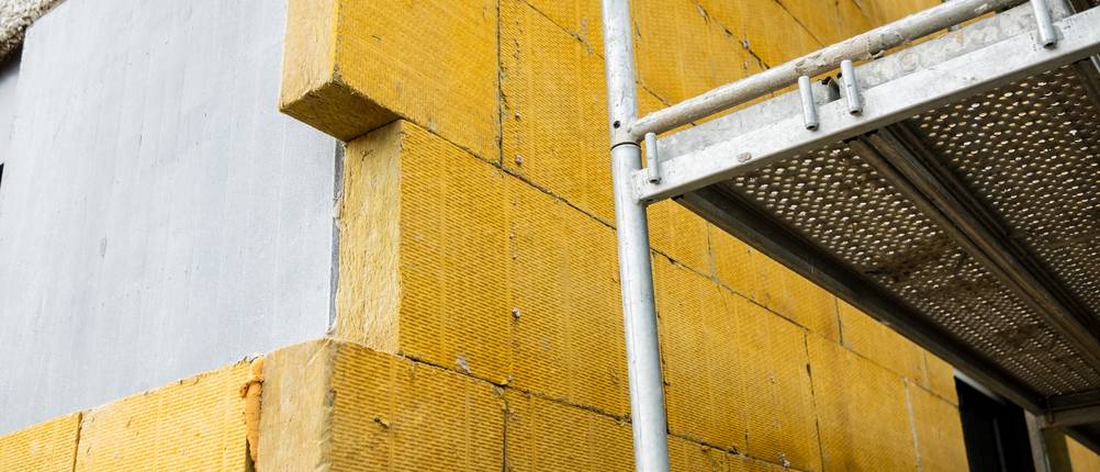 Die Wand eines Gebäudes wird mit Dämmplatten isoliert.