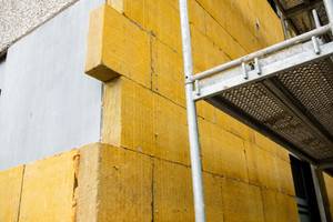 Test von Baufinanzierungen: Die Wand eines Gebäudes wird mit Dämmplatten isoliert.