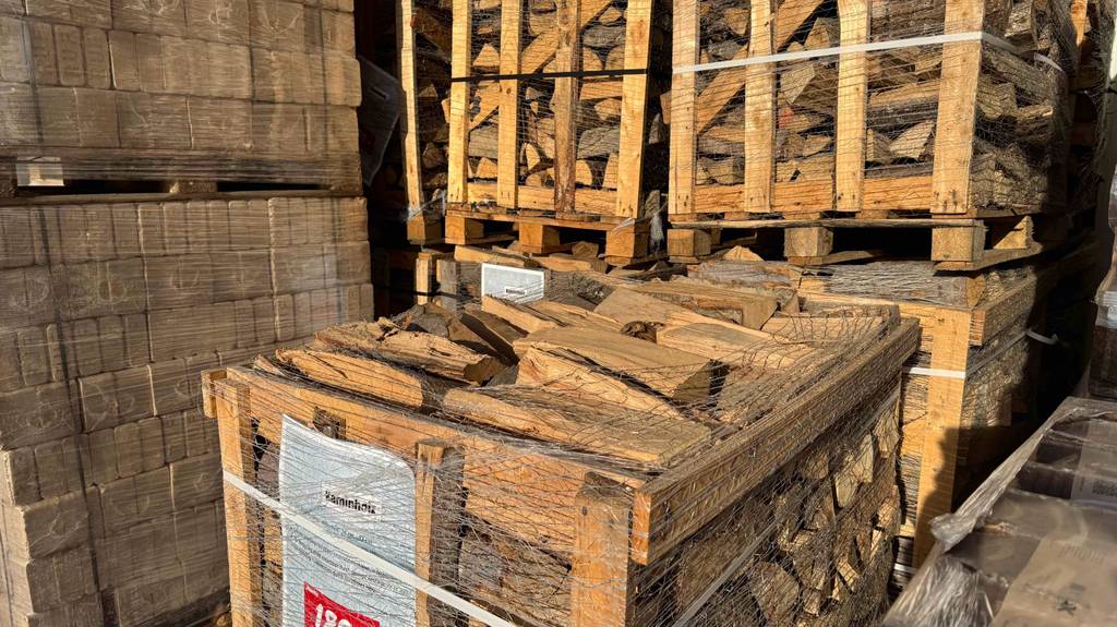 Mehrere Paletten mit Brennholz im Test befinden sich im Verkaufsbereich eines Baumarktes.