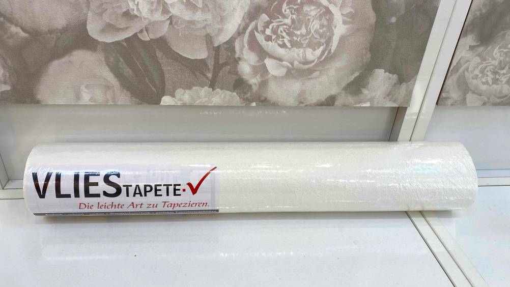 Vliestapete getestet: Eine in transparente Folie verpackte Rolle auf einer hellen Oberfläche.