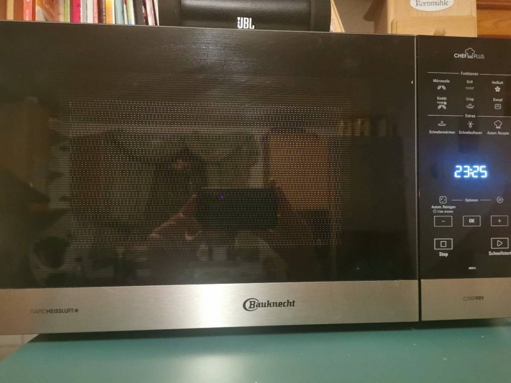 Bauknecht Mikrowelle im Test inklusive beleuchteter Uhranzeige steht in einem Wohnbereich.