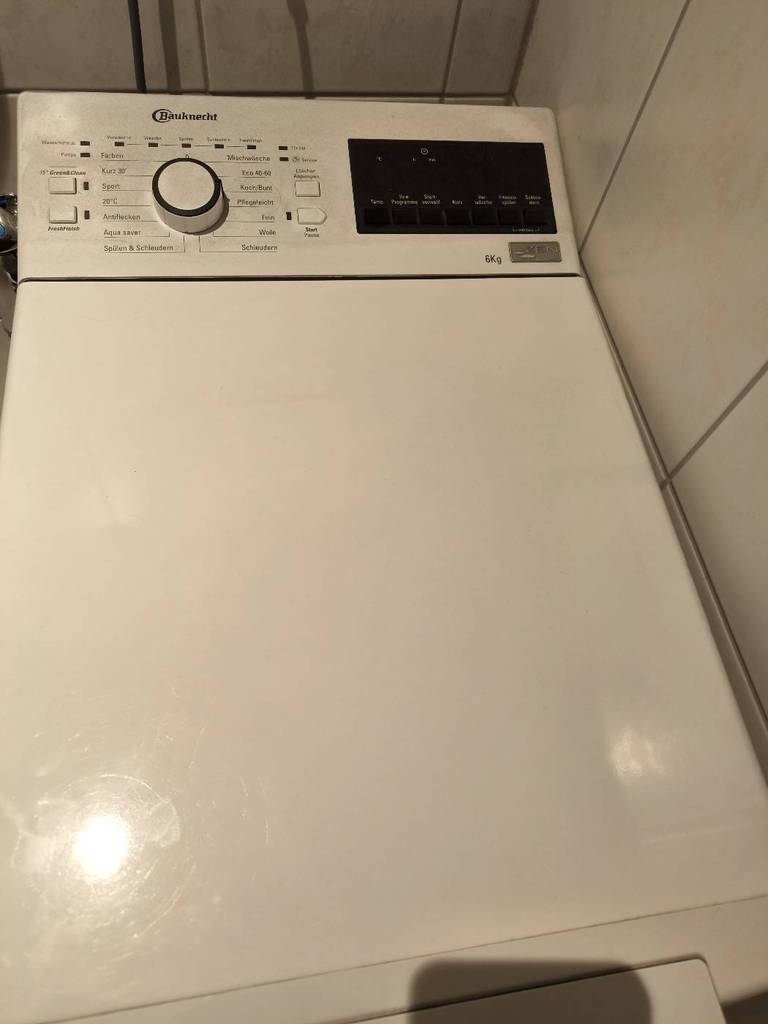 Ansicht von oben auf eine Bauknecht-Toplader-Waschmaschine im Test in einer weiß gefliesten Ecke.