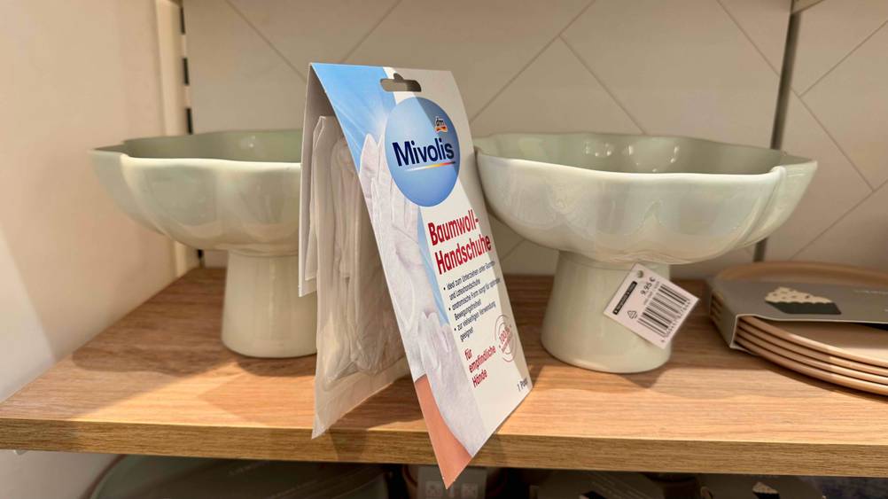 Seitenansicht der verpackten Baumwollhandschuhe im Test auf einem Regal.