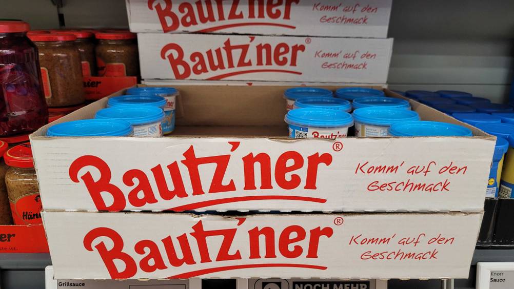 In einem Regal befinden sich Kartons mit mehreren Tiegel des Bautz'ner Senf im Test.