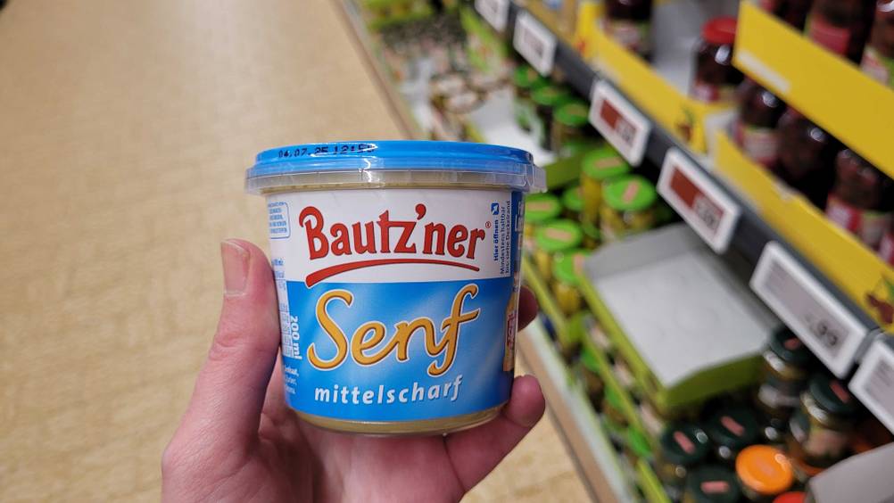 Eine Hand hält einen Tiegel des getesteten Bautz'ner Senfs.