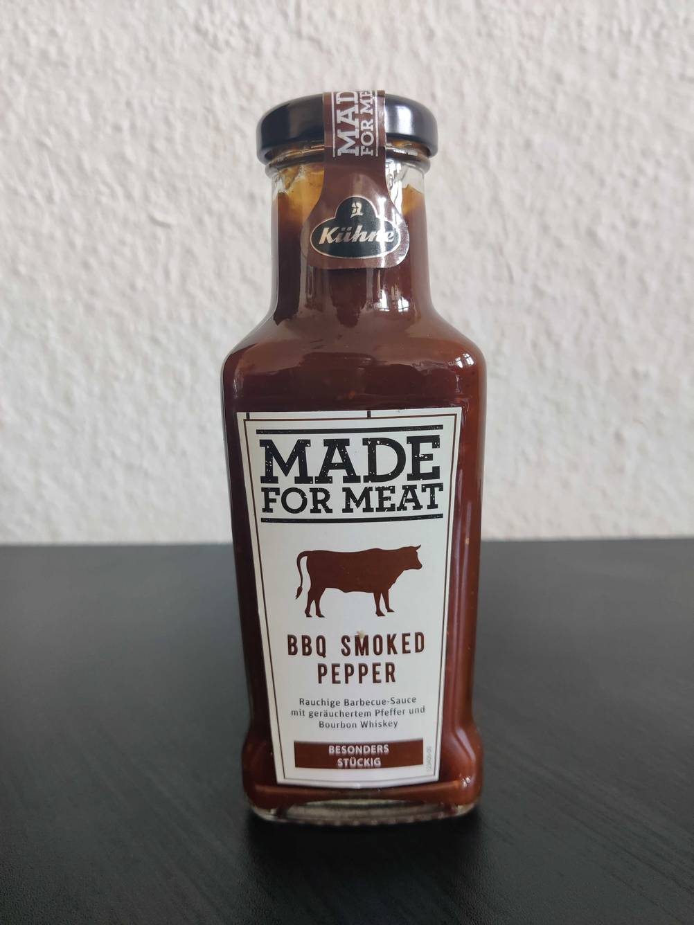 BBQ-Saucen getestet: Eine Flasche von vorne auf einer dunklen Fläche vor einer hellen Wand.