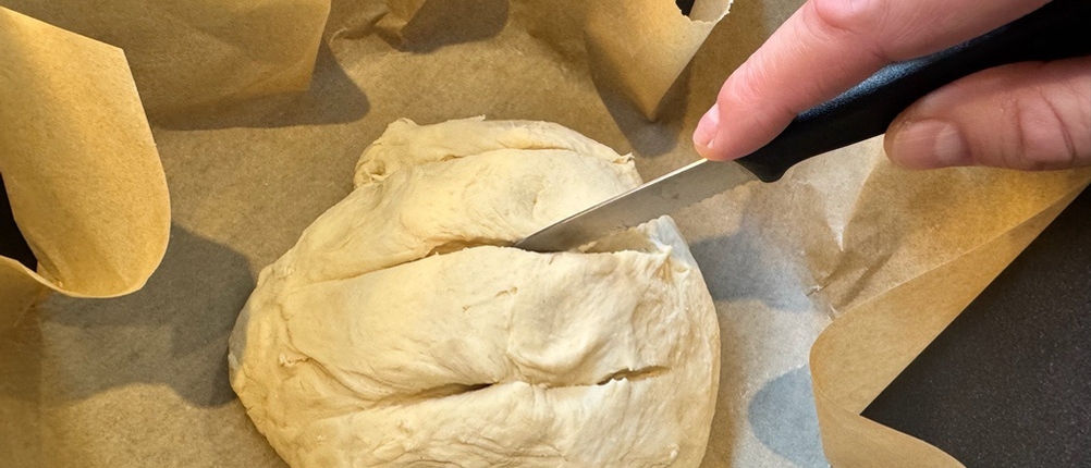 Mit einem Messer werden Spalte in Weißbrotteig geschnitten