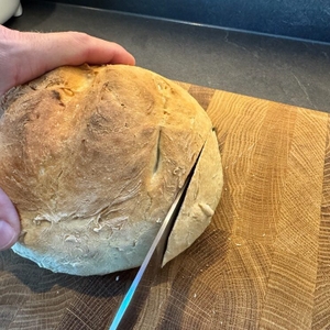 Der Anfang eines Weißbrots aus dem BBQ-Toro DO9P wird mit einem Messer geschnitten