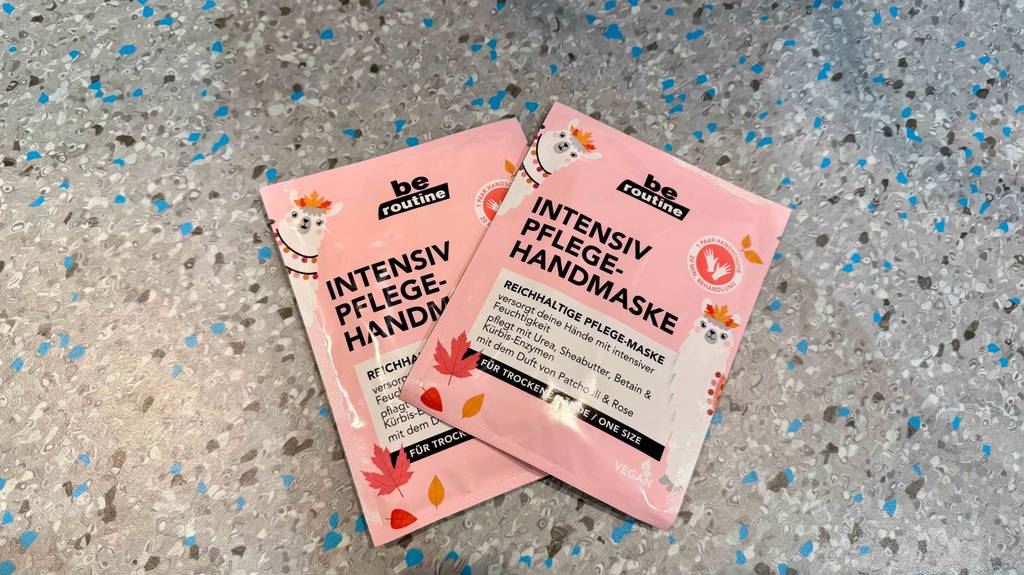 Zwei Packungen Handmaske liegen zum testen halb aufeinander auf einem Boden.