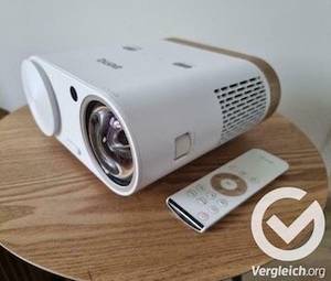Ein weißer Epson Beamer im Test steht neben der dazugehörigen Fernbedienung.