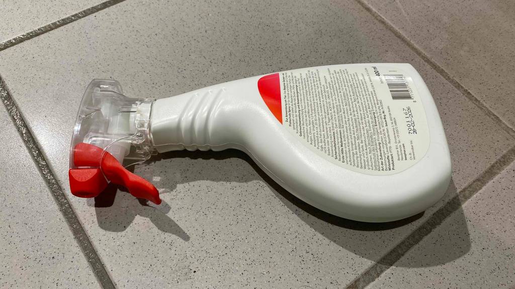 Eine Sprühflasche mit getestetem Beaphar-Zecken-Spray liegt mit rückseitiger Beschreibung nach oben auf einem Fliesenboden.