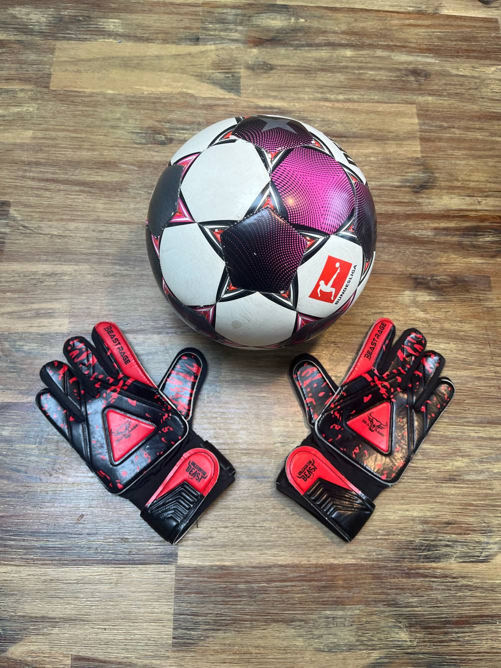 Im Test: Ein Fußball liegt zwischen einem Paar Torwarthandschuhe.