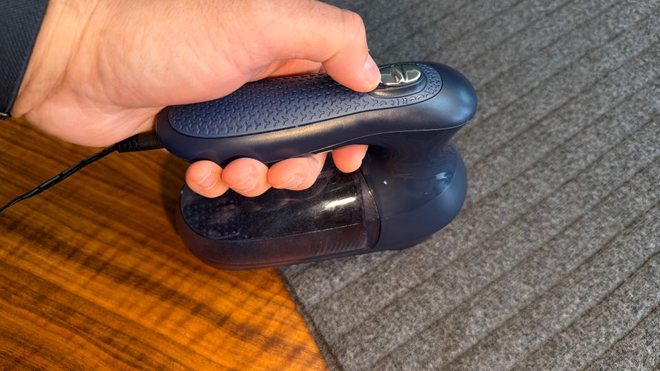 Eine Hand hält den Beautural ISJKL9889748 während der Rasur auf einem Pullover