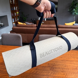 Eine Hand hebt die Beautyovo-Gymnastikmatte am Tragegurt hoch