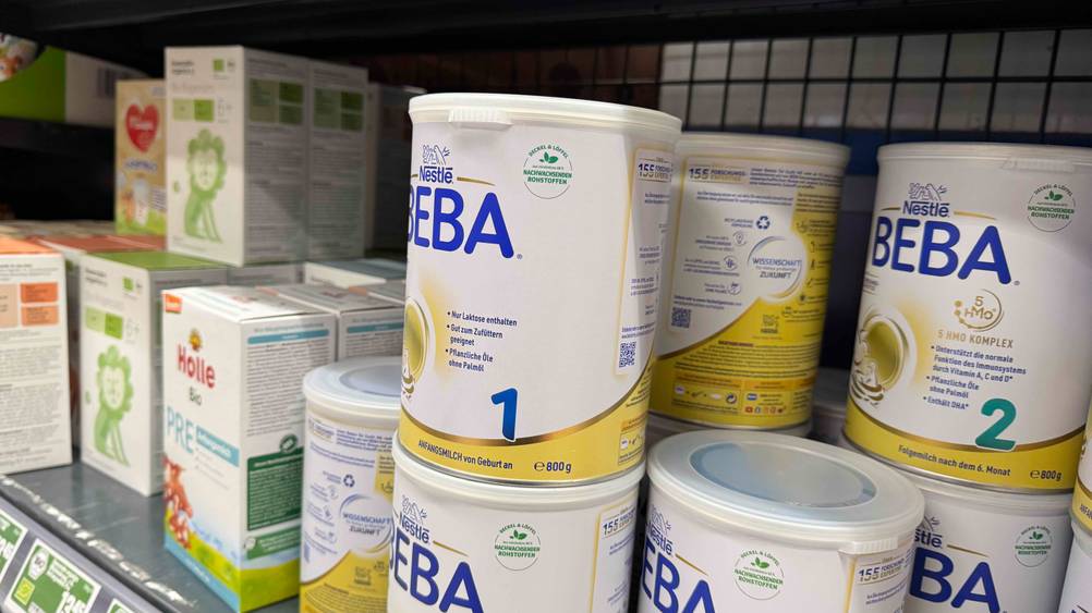 Mehrere Dosen der getesteten Beba-Babynahrung stehen neben anderen Produkten in einem Regal.