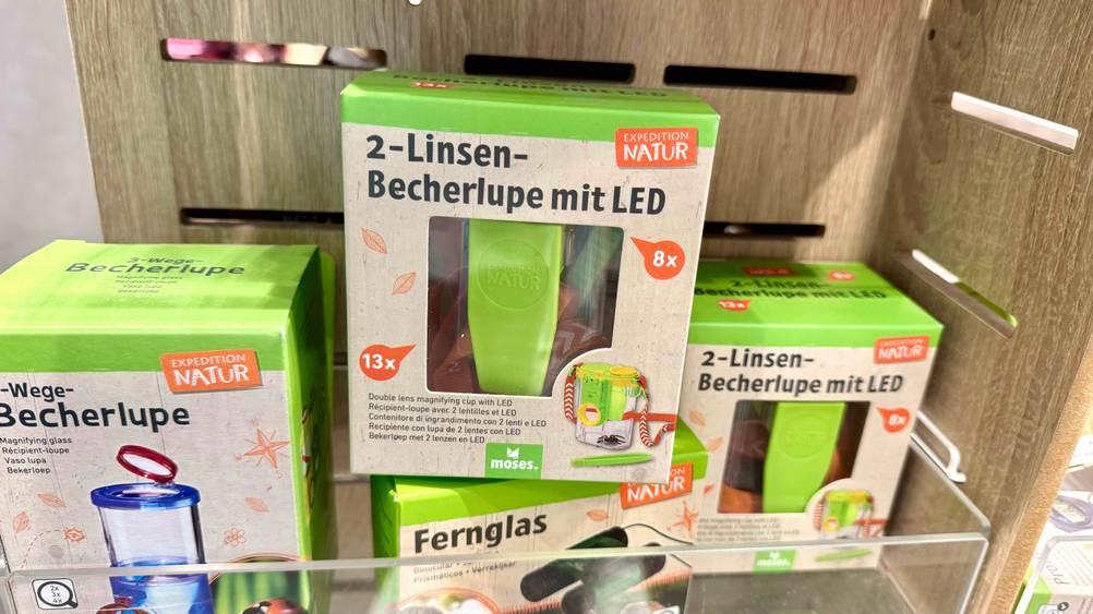 Die getestete Becherlupe mit anderen Produkten in einem Verkaufsregal.