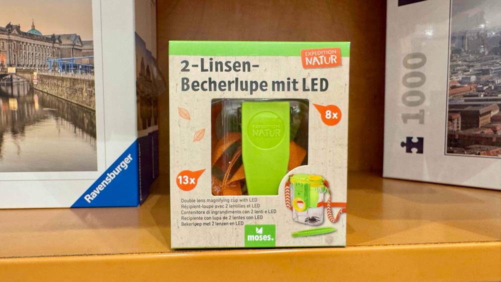 Getestet: Die Becherlupe in einem Regal neben Puzzeln.