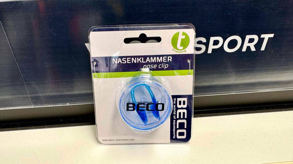 Nasenklammer zum Schwimmen im Test: Eine Nasenklammer steht in Originalverpackung vor einer blauen Leiste.