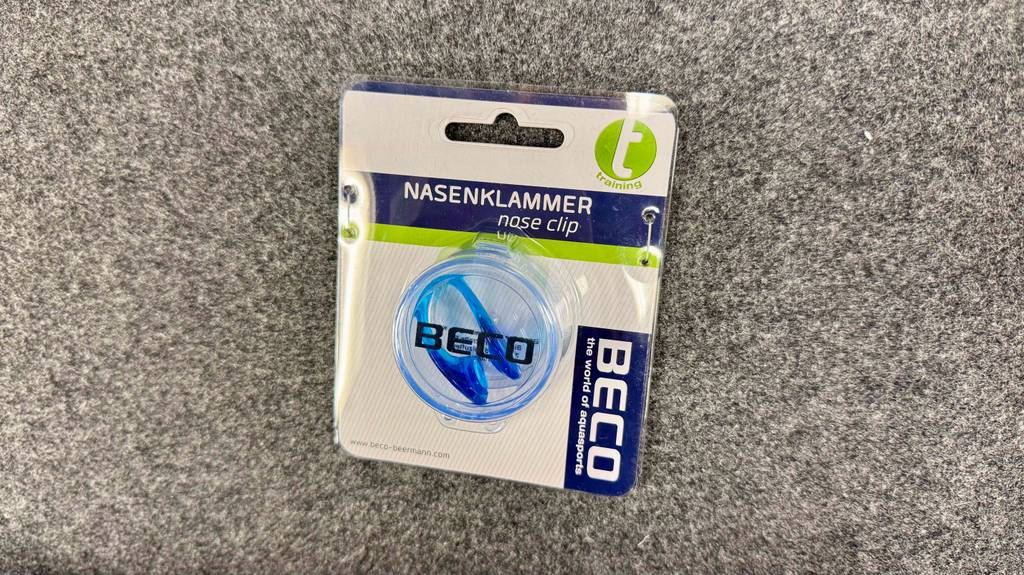 Nasenklammer zum Schwimmen im Test: Eine Packung mit einer Nasenklammer zum Schwimmen liegt auf einer Vliesfläche.