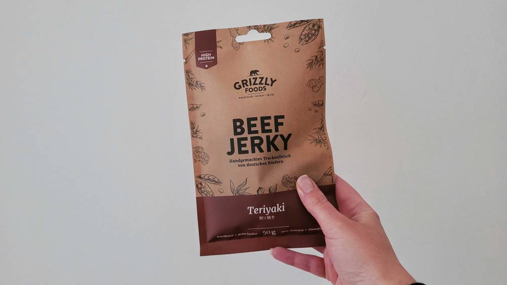 Eine Hand hält eine Packung Beef Jerky im Test vor eine helle Wand.