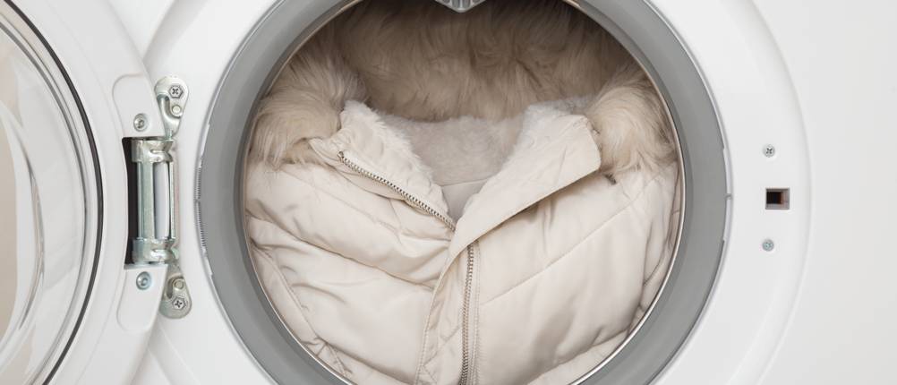 Beheizbare Jacken für Damen im Test: cremefarbene Winterjacke, die sich in einer Waschmaschine befindet