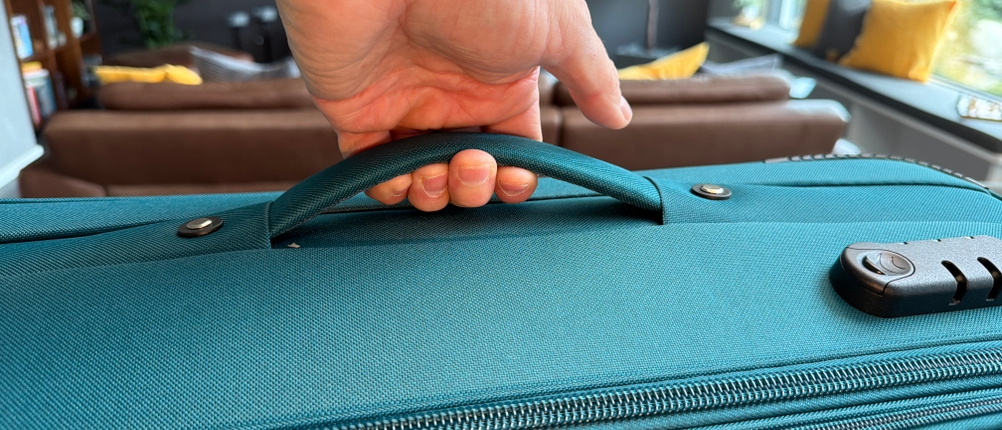 Eine Hand hebt den Beibye-4-Rollen-Reisekoffer am Griff hoch