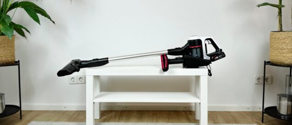Ein Akkustaubsauger liegt quer auf einem weißen Tisch zwischen zwei Pflanzen. Der Staubsauger ist vollständig montiert.