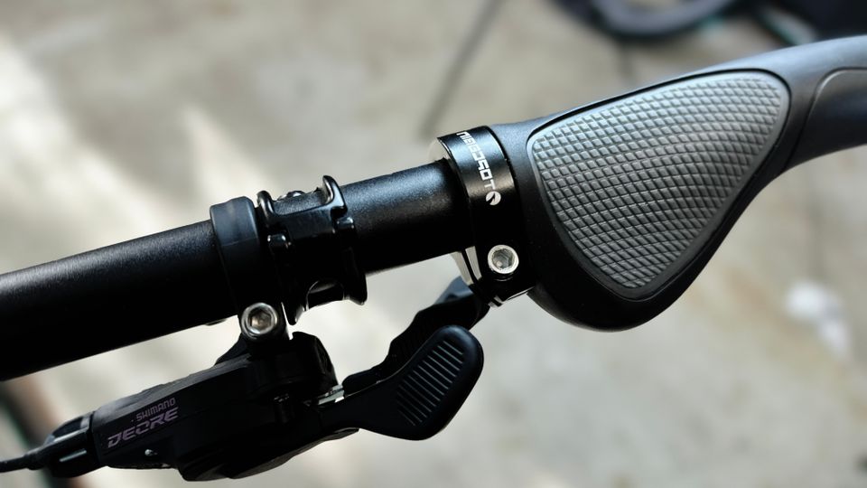 Ein montierter ergonomischer Fahrradgriff ist am Lenker zu sehen. Die Kamera fokussiert auf Textur und Form des Griffdesigns.