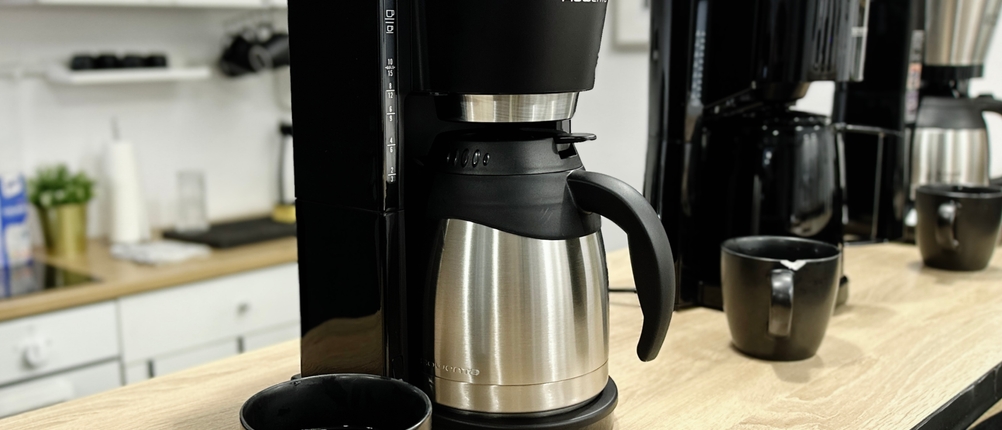 Die Rowenta Milano CT3818 steht mit zwei weiteren Kaffeemaschinen und Tassen nebeneinander auf einer Holzplatte. Der Fokus liegt auf dem Produktvergleich.